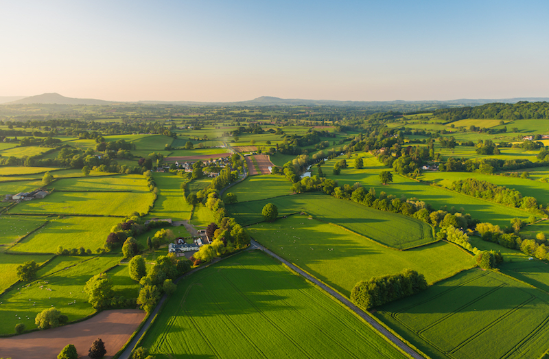 Aerial photograph of green farms and rural dwellings in the Cotswolds.